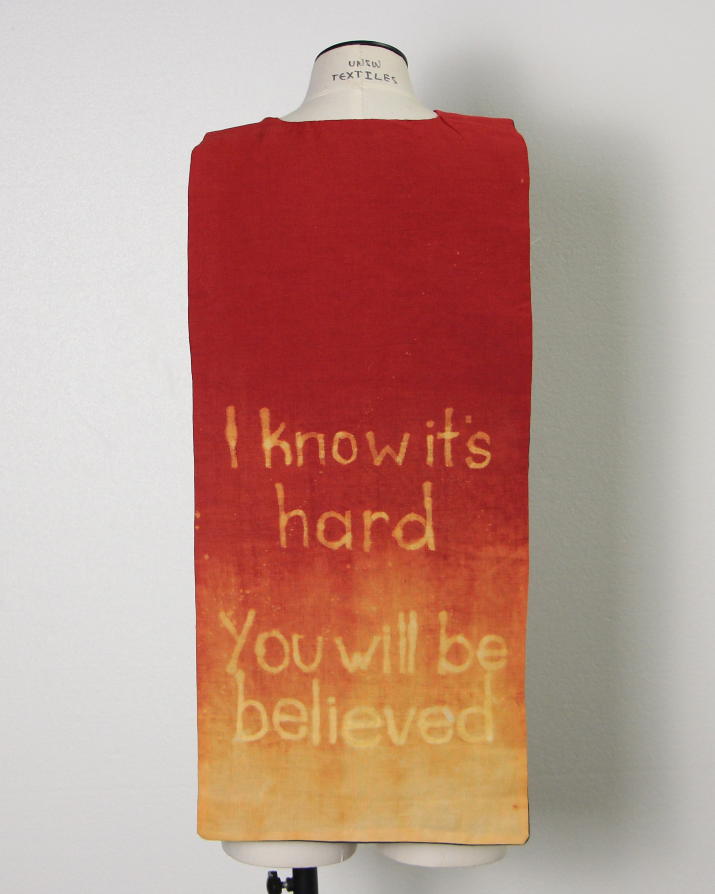 Bleached red lining of cape reading I know it's hard, you will be believed